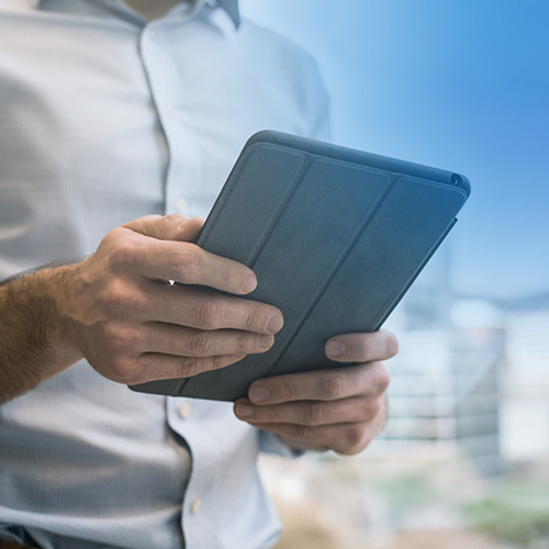 Man standing outside holding a tablet in both hands.